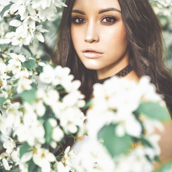 Outdoor fashion photo of beautiful young woman surrounded by flowers of apple-tree. Spring blossom. Summer vibes